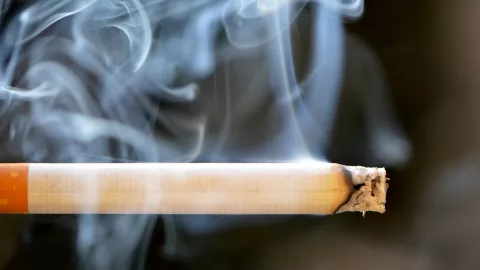 Close up of a cigarette smoking with ash on its tip