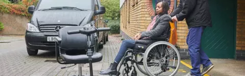 Woman in wheelchair next to a car