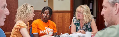A group of people sitting round a table sharing their MS stories