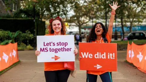 MS Society supporters holding signs saying 'Let's stop MS together' and 'We did it!'