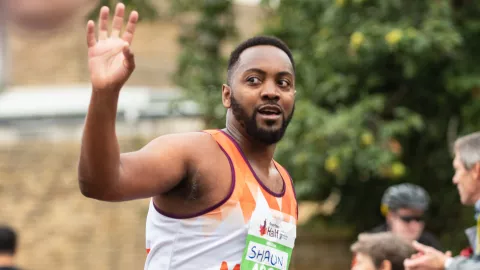 A man in an MS Society t-shirt running a marathon and waving