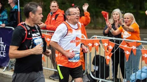 A man running a marathon with MS Society supporters cheering him on