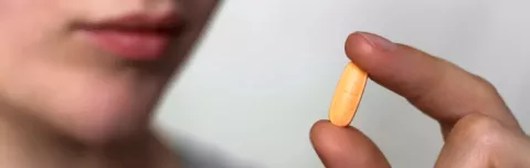 A person holding an orange pill 