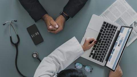 Doctor showing someone a web page on a laptop
