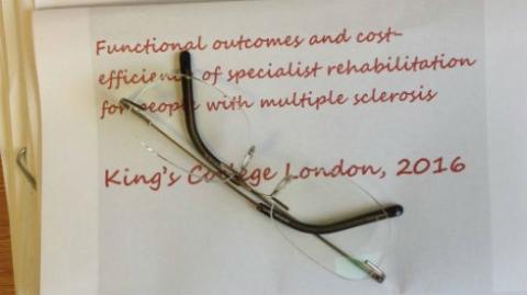 Image shows a research paper with spectacles on a desk
