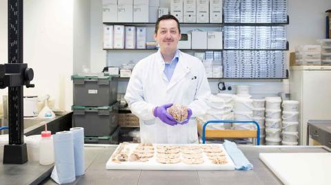 A tissue bank researcher stands in a lab in front of a tray of tissue samples