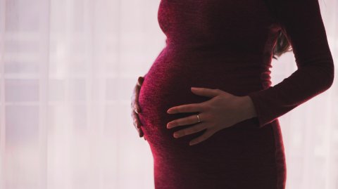 A pregnant woman with her hands on her bump